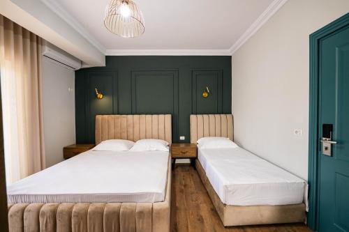 two beds in a room with green walls at Kristianna Apartments in Dhërmi
