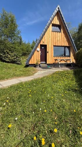 a small wooden building with a grassy field in front at 1 Bedroom Cabin with Mountain & Loch Views - Quiet Location between Glencoe & Ben Nevis in Onich