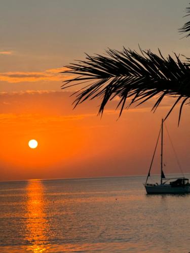 a sail boat in the ocean at sunset at Blue Harmony Hotel in Kinion