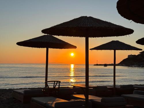a group of umbrellas and chairs on a beach with the sunset at Blue Harmony Hotel in Kinion