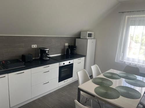 una cucina con tavolo e una cucina con armadietti bianchi di Olivér 22 Apartman a Fonyód