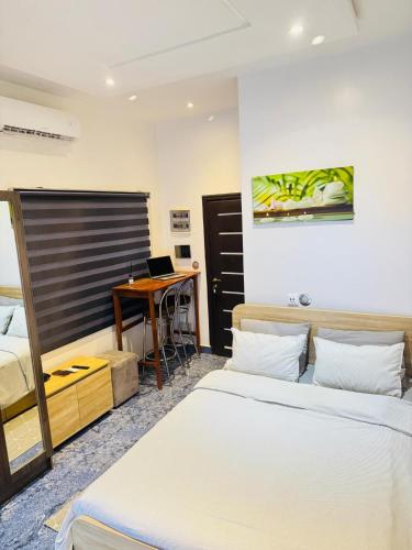 a bedroom with two beds and a desk with a laptop at RESIDENCE MH SERVICES Cotonou in Cotonou