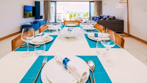 a dining room with a long table with chairs and glasses at Latitude By Horizon Holidays in Rivière Noire