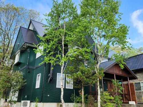 a green house with a black roof at Pension Green Lake in Gujo