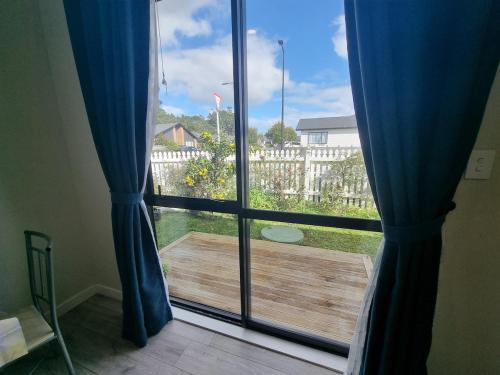 a window with a view of a wooden deck at BEHOME - Modern Guest Suite in Kumeu