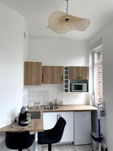 une cuisine avec des armoires blanches et une table et des chaises dans l'établissement Lumineux & Chic sur Villars, à Valenciennes