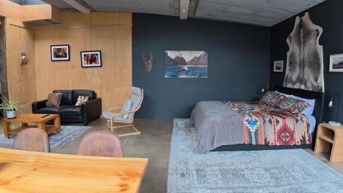 a bedroom with a bed and a couch and a chair at Blue Mountains Loft, Tapanui in Glenkenich