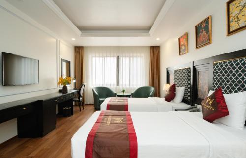 a hotel room with two beds and a television at MT Collection Hotel Ha Long in Ha Long