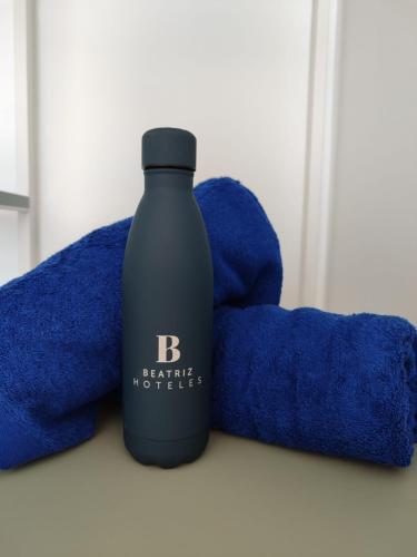 a bottle of shampoo sitting next to blue towels at Hotel Calella by Beatriz Hoteles in Calella