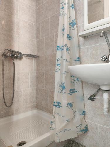 a bathroom with a shower curtain and a sink at Niki Rooms in Tinos