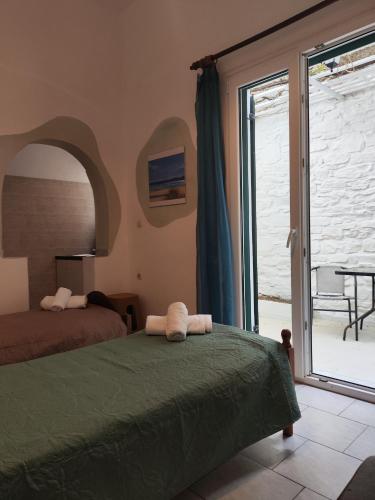 a bedroom with a bed and a sliding glass door at Niki Rooms in Tinos
