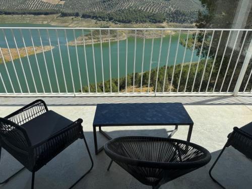 a balcony with two chairs and a table and a lake at Casa Trece in Iznájar