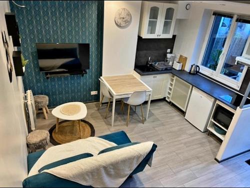 Il comprend une cuisine et un salon avec une table. dans l'établissement Maison terrasse proche mer, à Douvres-la-Délivrande