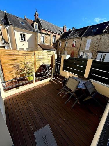Elle comprend un balcon avec deux chaises et une terrasse en bois. dans l'établissement Maison terrasse proche mer, à Douvres-la-Délivrande