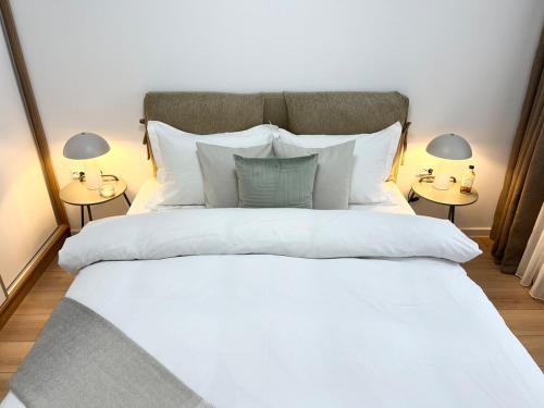 Un dormitorio con una gran cama blanca con dos lámparas. en Comfort Modern Central Apt, en Haskovo