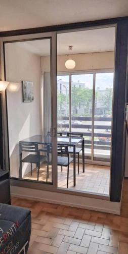 - un salon avec une grande porte coulissante en verre, une table et des chaises dans l'établissement Studio en bord de mer, à Saint Cyprien Plage
