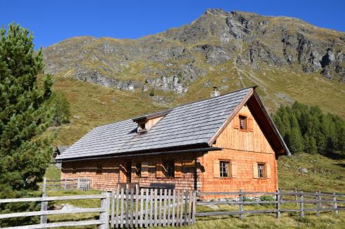 a wooden barn with a fence in front of a mountain at Karnerhof in Mariapfarr