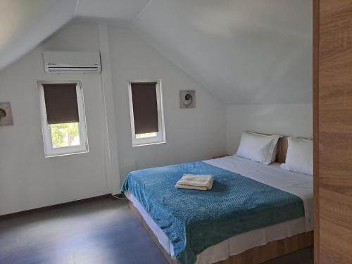 a white bedroom with a bed with a blue blanket at CAZARE EDI in Corbu