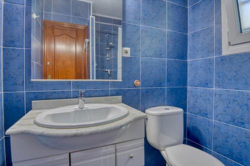 Un baño con azulejos azules, lavabo e inodoro. en Escale, en Pals