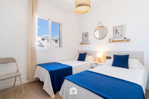 a room with two beds and a chair and a window at Mediterranean Way - Punta Prima 17 in La Pineda