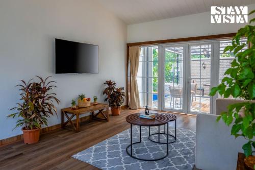a living room with a tv and a table at StayVista at The Five Oaks - Private Pool Cottages in Karjat