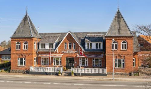 a large brick building with two towers on a street at Gredstedbro Hotel in Gredstedbro
