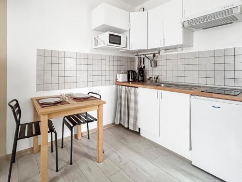 a kitchen with white cabinets and a wooden table and chairs at Studio Bien placé Centre Historique de Saintes in Saintes
