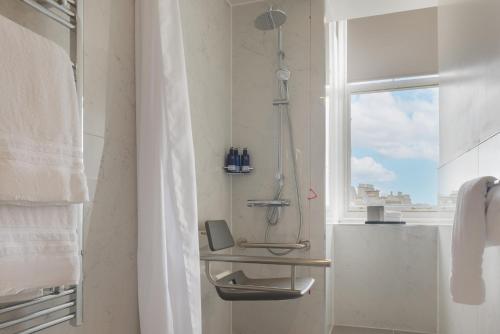 a shower in a bathroom with a window at The Caledonian Edinburgh, Curio Collection by Hilton in Edinburgh
