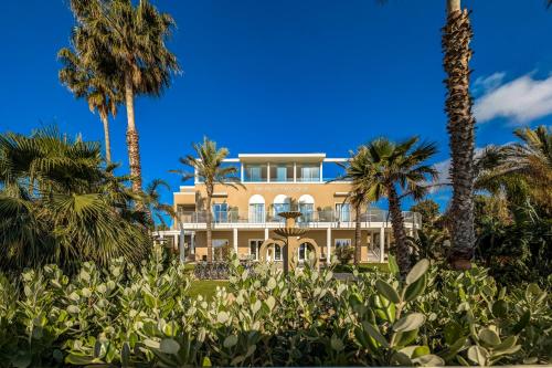 Una casa grande con palmeras al frente. en Hotel Nautilus Excelsior - Adults Only, en Cagliari