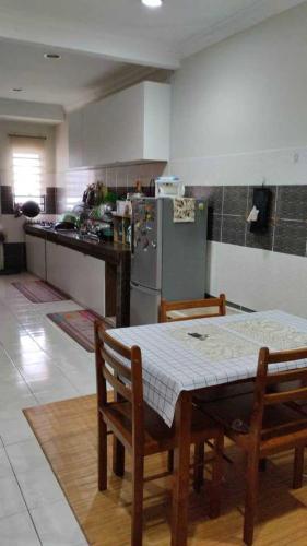 a kitchen with a table and chairs and a refrigerator at ISLAMIC HOMESTAY CASA NAUFAL FULLY AIRCOND for 1LR 3BR in Port Dickson