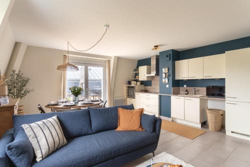un salon avec un canapé bleu et une cuisine dans l'établissement Kerlibri - 15min à Pied de la Plage, à Dinard
