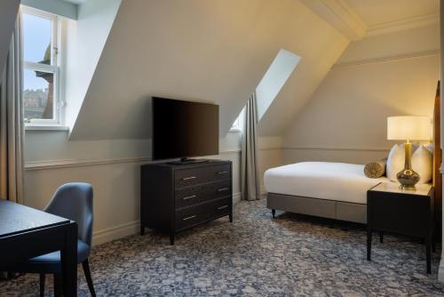 a bedroom with a bed and a tv and a desk at The Caledonian Edinburgh, Curio Collection by Hilton in Edinburgh