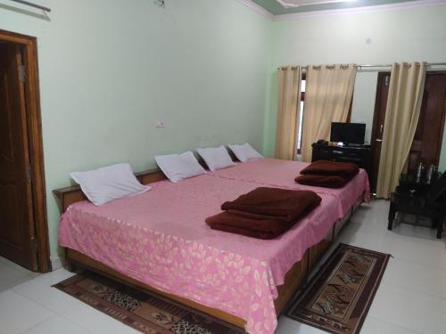 a bedroom with a large pink bed with brown blankets at Hotel Sandeep palace in Jāmb