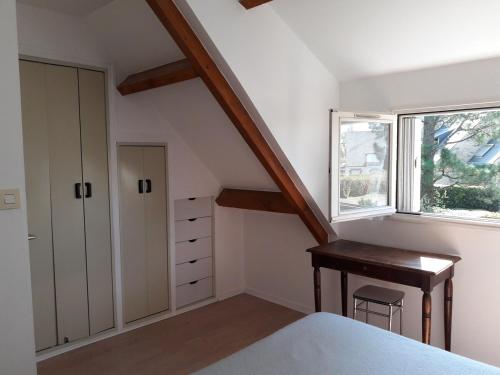 - une chambre mansardée avec un bureau et une fenêtre dans l'établissement Les Galiotes - Maison à Carnac proche plage, à Carnac