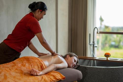 a woman giving a woman a massage in a bath tub at Emana Akatara in Ubud