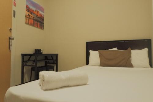 a bedroom with a white bed with a pillow on it at Brightwood Hotel & Residences in Manila