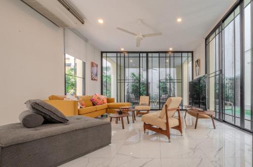 a living room with a couch and chairs and windows at Sukumvit Pool Villa 5BR 5-7min-walk to Thonglor Sky train in Klong Toi
