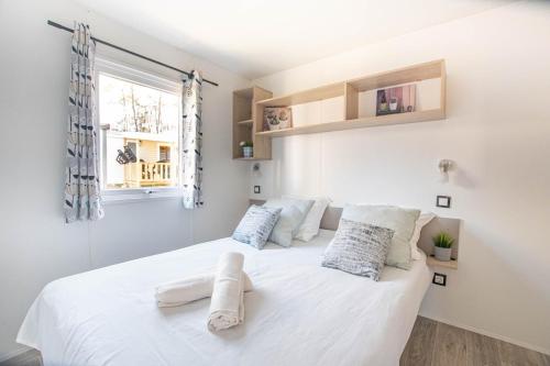 une chambre blanche avec un grand lit blanc avec des oreillers dans l'établissement Sekoya Lodge, Mobile Home 500m de la plage, à Seignosse