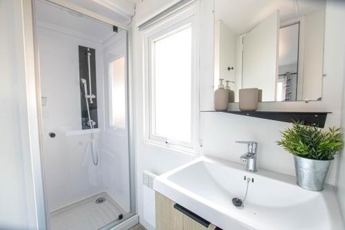 une salle de bain blanche avec un lavabo et un miroir dans l'établissement Sekoya Lodge, Mobile Home 500m de la plage, à Seignosse