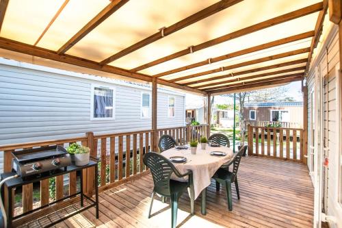 un patio avec une table et des chaises sur une terrasse dans l'établissement Sekoya Lodge, Mobile Home 500m de la plage, à Seignosse