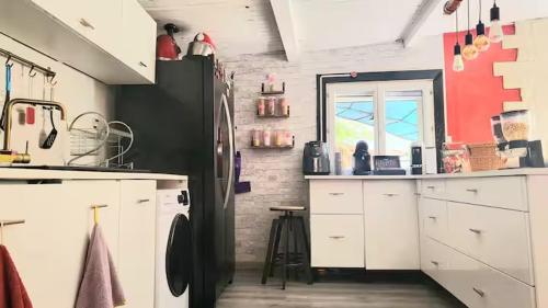 a kitchen with white cabinets and a black refrigerator at Havre de paix Avignon avec Jacuzzi & Sauna in Avignon
