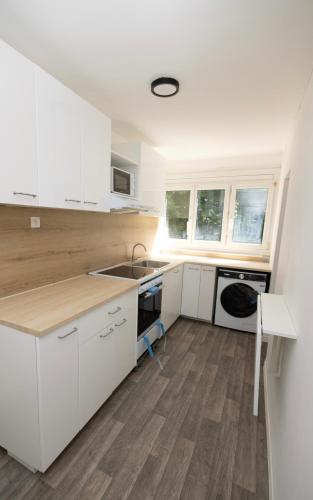 une cuisine avec des armoires blanches et un plancher en bois dans l'établissement Chambres Privées Gagny Paris 20 min, à Gagny