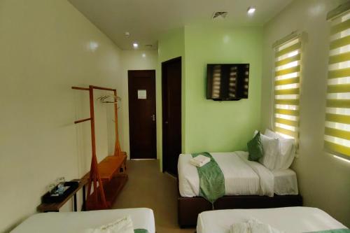 a hotel room with two beds and a window at Manuela Suites Puerto Princesa near Airport in Puerto Princesa City