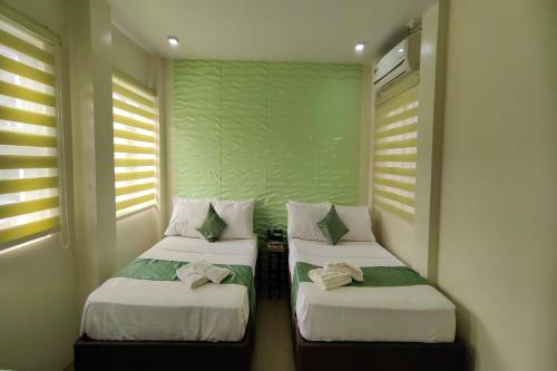 two beds in a room with two windows at Manuela Suites Puerto Princesa near Airport in Puerto Princesa City