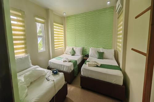 a room with two beds and two windows at Manuela Suites Puerto Princesa near Airport in Puerto Princesa City