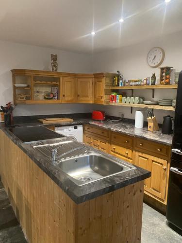 a kitchen with a large sink and wooden cabinets at Hideaway Cottage in Camelford