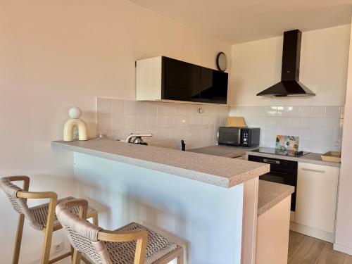 - une cuisine avec un comptoir et des chaises dans l'établissement Deux pièces tout confort sur les hauteurs de Propriano, à Propriano