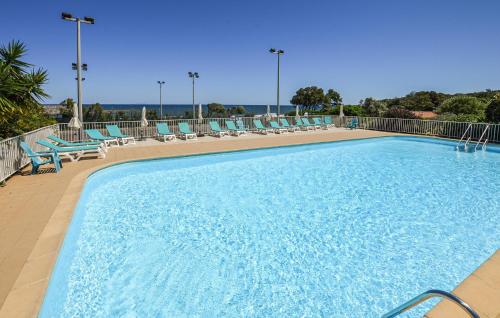 une grande piscine avec des chaises bleues dans l'établissement Pet Friendly Apartment In Cervione, à Cervione