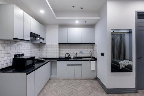 a kitchen with white cabinets and black counter tops at BedChambers Serviced Apartments, MG ROAD in Gurgaon