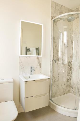 a white bathroom with a shower and a sink at George Apartments in Broadway
